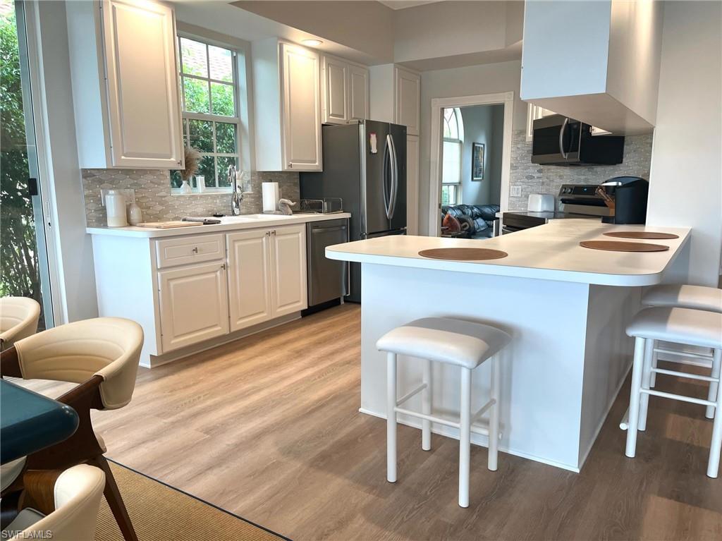 5477 Freeport Lane Naples, FL 34119 - Photo 9 of 36 a kitchen with kitchen island a dining table and chairs