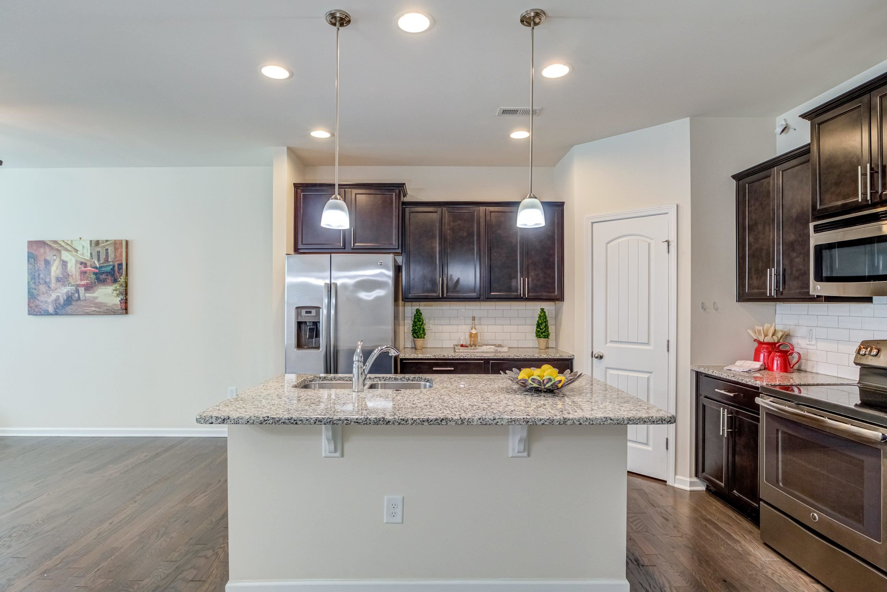 7817 Elmshire Way Raleigh, NC 27616 - Photo 11 of 46 a kitchen with stainless steel appliances a sink dishwasher a microwave oven a stove and a refrigerator with wooden floor