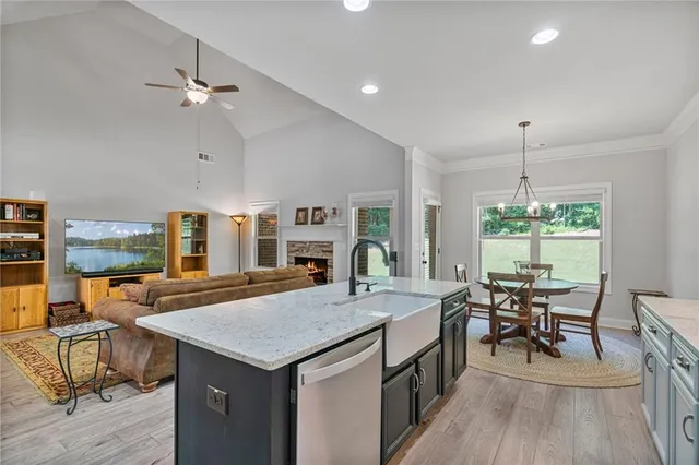 a open kitchen with stainless steel appliances granite countertop a stove top oven a dining table and chairs with wooden floor