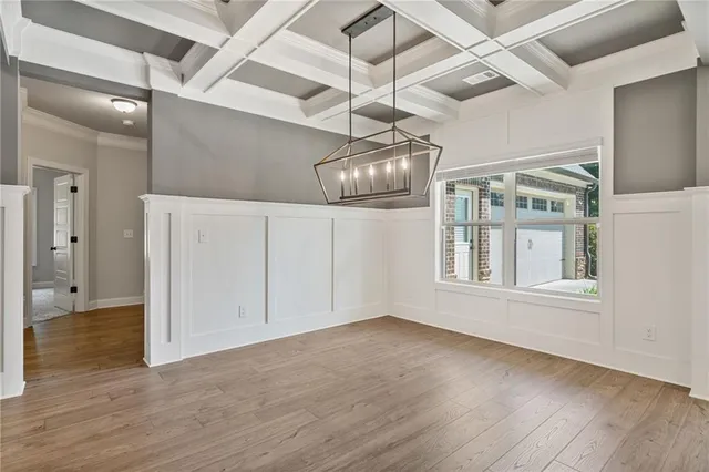 a view of an empty room with wooden floor and a ceiling fan
