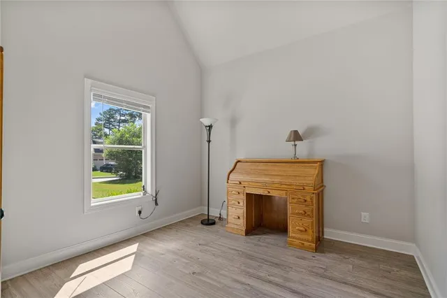 a view of an empty room with wooden floor windows and a fireplace