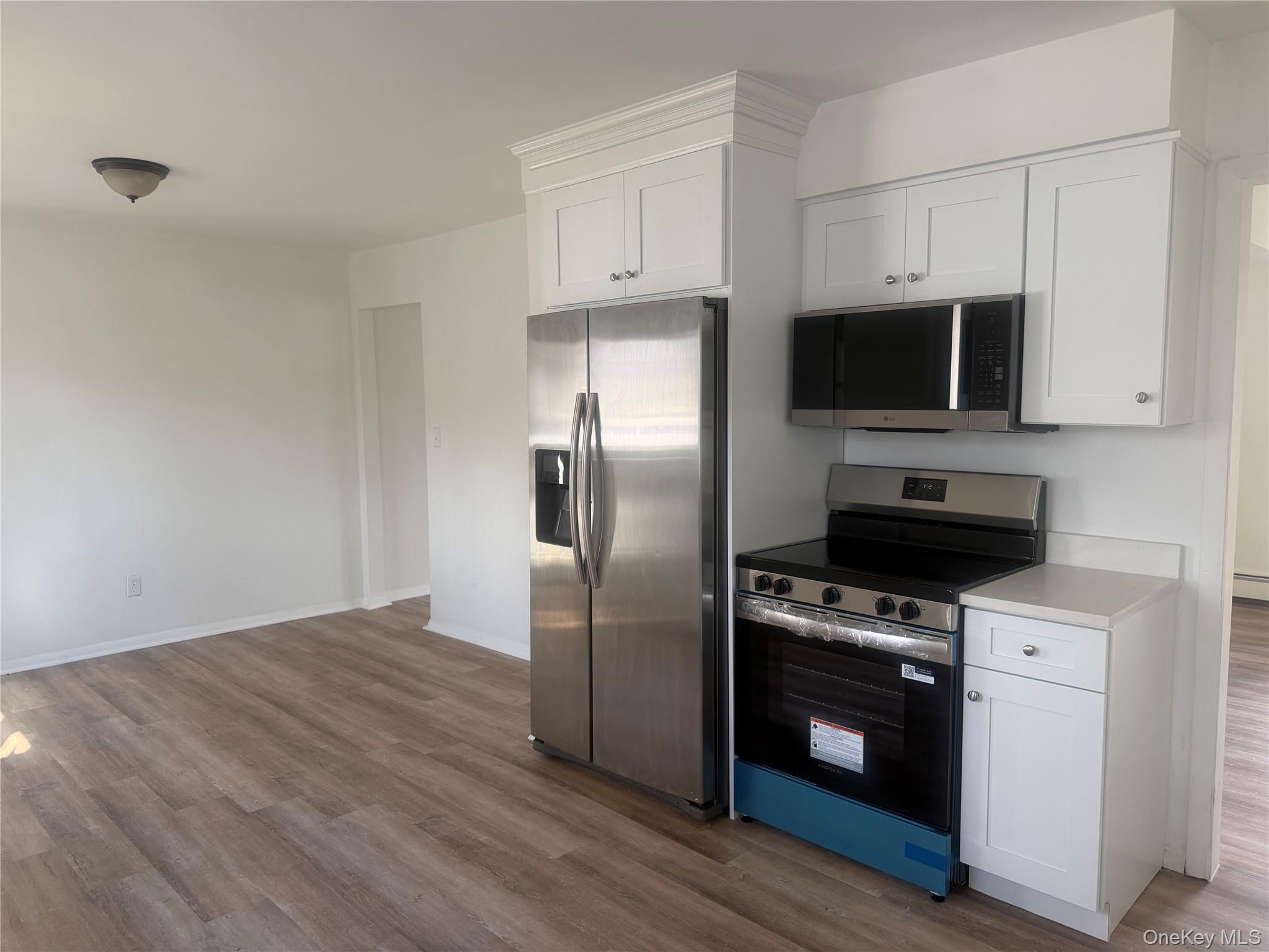 7 Filmore Avenue Coram, NY 11727 - Photo 8 of 22 a kitchen with granite countertop a stove a microwave a refrigerator a sink and dishwasher with wooden floor
