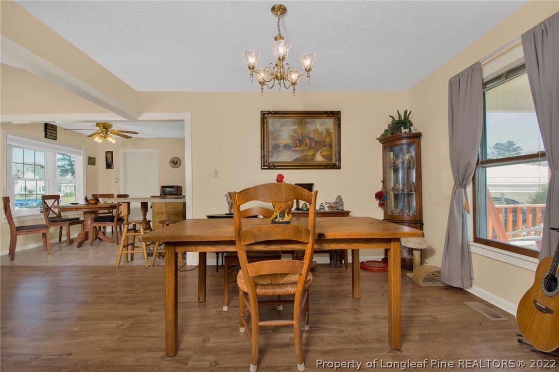 1197 Rowan Road Lumberton, NC 28358 - Photo 6 of 37 a dining room with wooden floor a chandelier a glass table and chairs