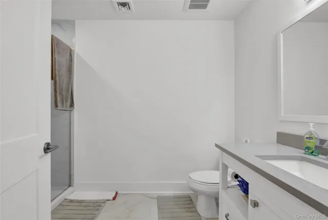 a bathroom with a toilet a sink a mirror a shower and vanity