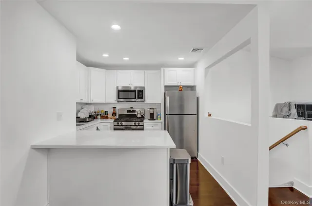 a kitchen with a refrigerator a stove top oven a counter space and wooden floor