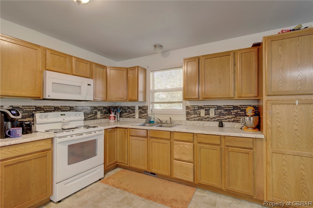 354 Weems Road Weems, VA 22576 - Photo 3 of 24 Kitchen featuring light tile floors, sink, white appliances, and backsplash