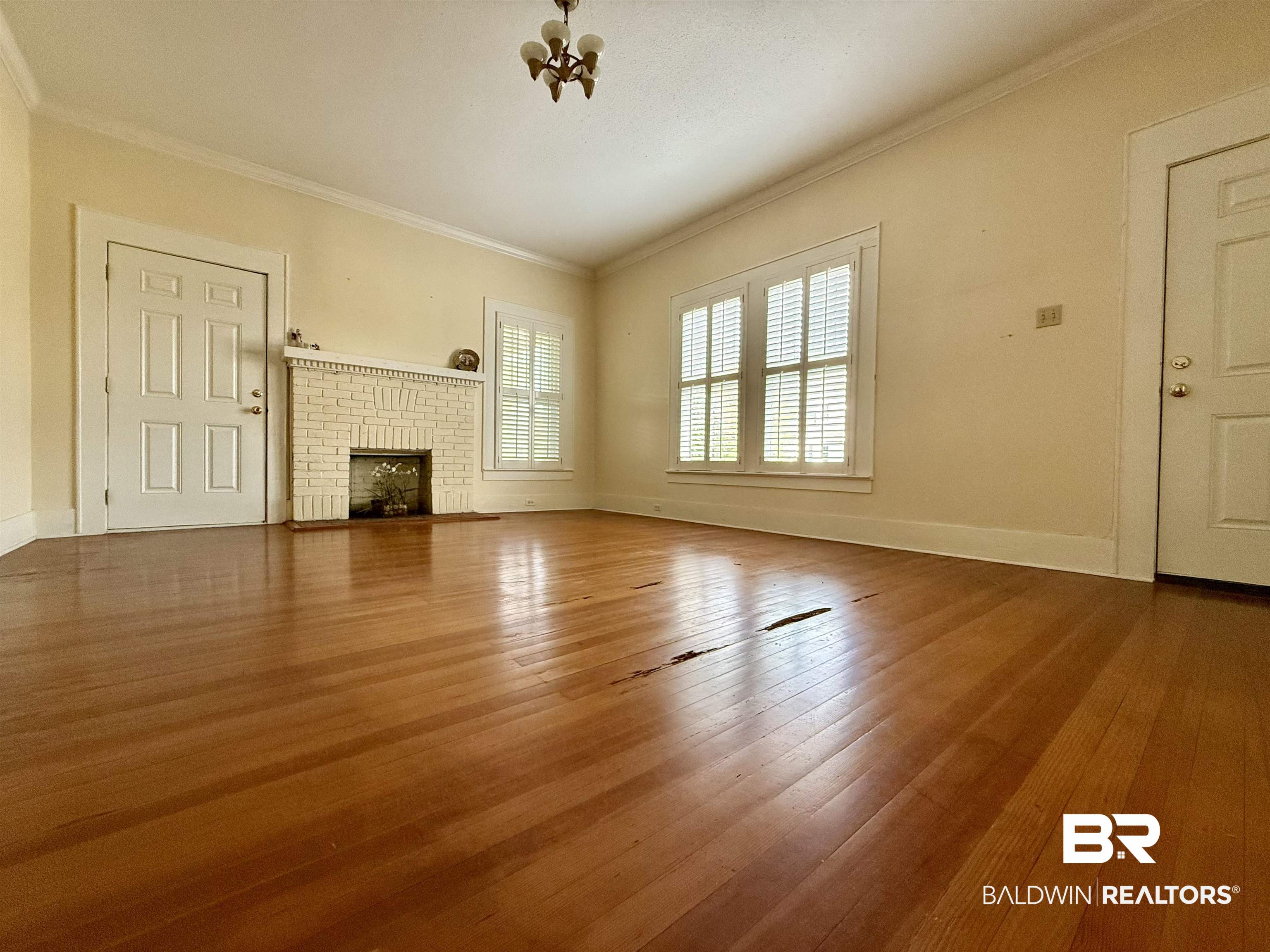 423 Evergreen Avenue Brewton, AL 36426 - Photo 6 of 18 Unfurnished living room with a fireplace, ornamental molding, and wood-type flooring