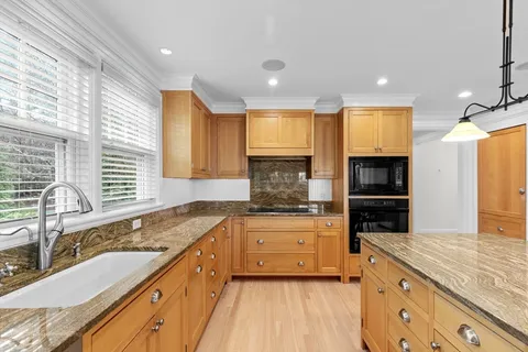 a large kitchen with stainless steel appliances granite countertop a sink and cabinets