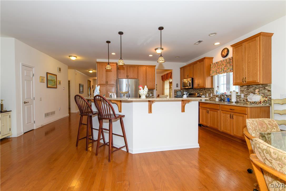1023 Resolution Drive Bethlehem, PA 18017 - Photo 12 of 26 a kitchen with stainless steel appliances granite countertop a stove top oven a sink a dining table and chairs with wooden floor