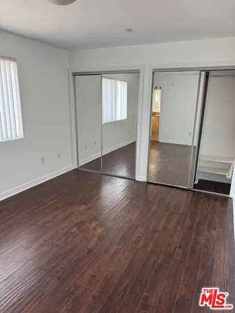 an empty room with wooden floor and staircase