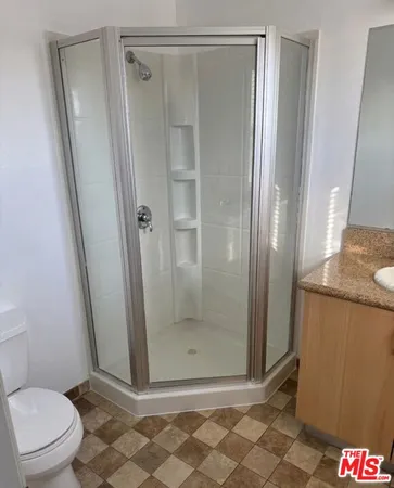 a bathroom with a granite countertop shower and a toilet