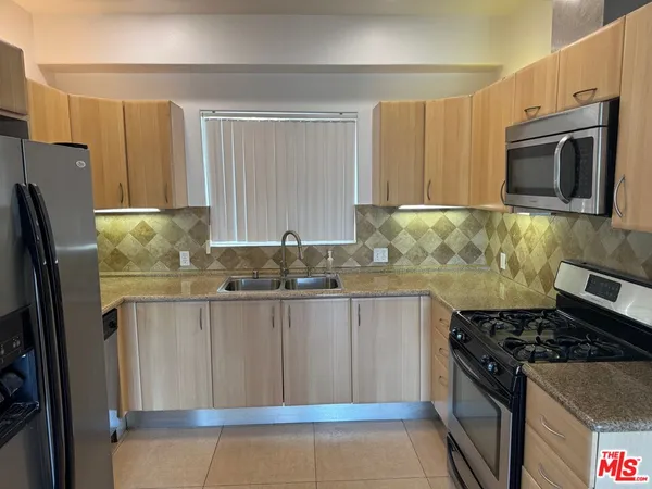 a kitchen with stainless steel appliances granite countertop a refrigerator stove top oven and sink