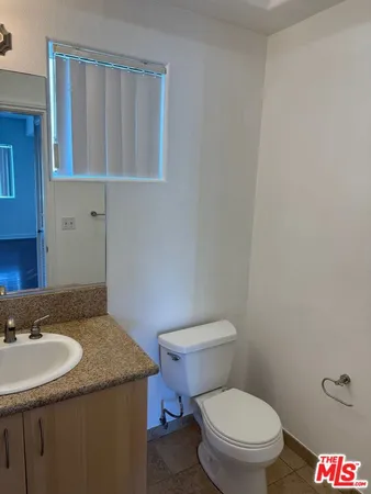 a bathroom with a granite countertop sink and a toilet