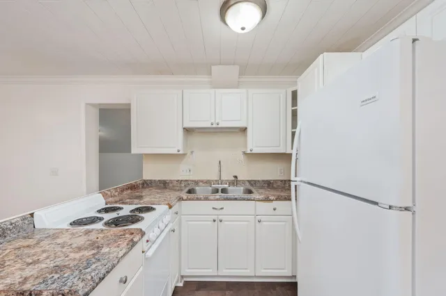 a kitchen with granite countertop a sink stove and refrigerator