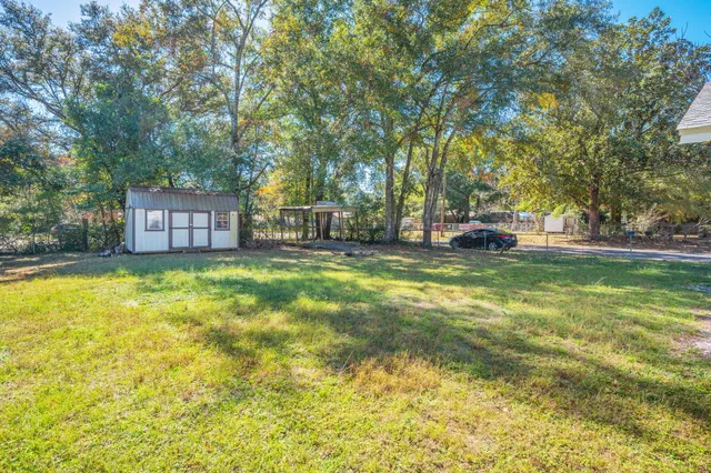 a view of a house with a big yard and large trees