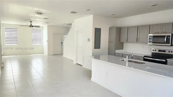 a kitchen with stainless steel appliances a sink a stove a microwave a refrigerator a counter top space and cabinets