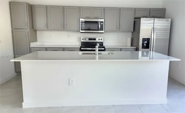 a kitchen with granite countertop a refrigerator and a stove top oven
