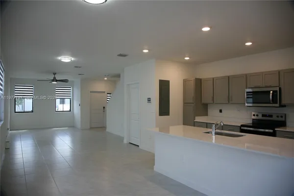 a open kitchen with stainless steel appliances granite countertop a refrigerator a sink a stove and a microwave oven with wooden floor