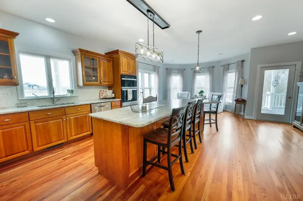 a open kitchen with stainless steel appliances granite countertop a refrigerator a sink dishwasher a stove and a dining table with wooden floor