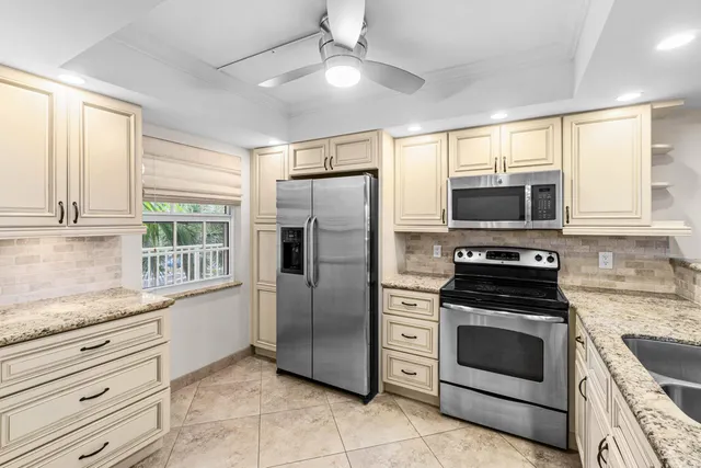 a kitchen with granite countertop a refrigerator stove and microwave