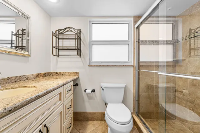 a bathroom with a granite countertop toilet a sink and a window