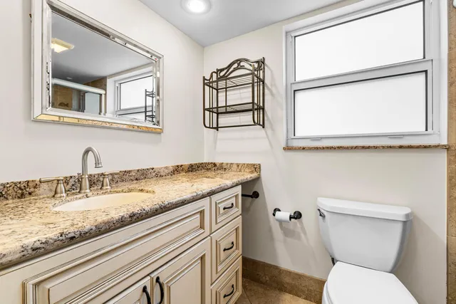 a bathroom with a granite countertop toilet sink and mirror