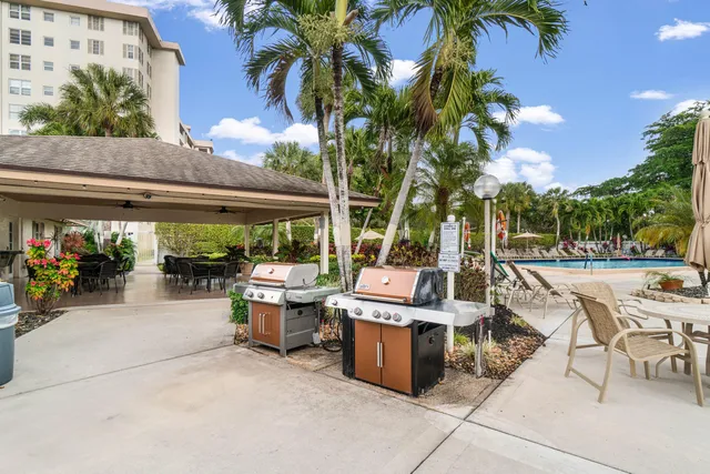 a view of a patio with dining table and chairs under an umbrella with a fountain