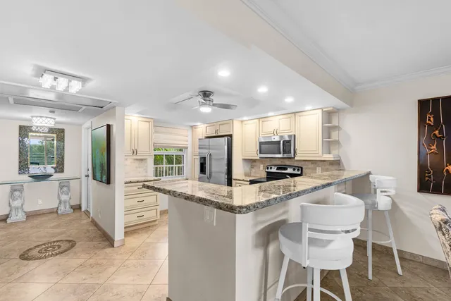 a kitchen with stainless steel appliances kitchen island granite countertop a table and chairs in it