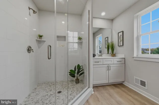 a bathroom with a granite countertop sink a mirror a vanity and a shower