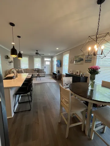 a dining room with stainless steel appliances kitchen island granite countertop a table chairs and a refrigerator