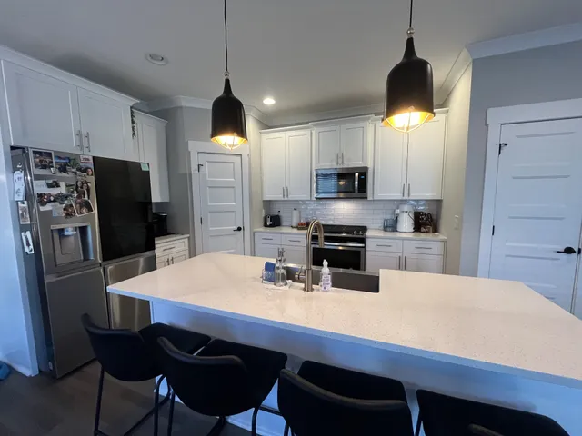 a kitchen with stainless steel appliances a dining table chairs refrigerator and microwave