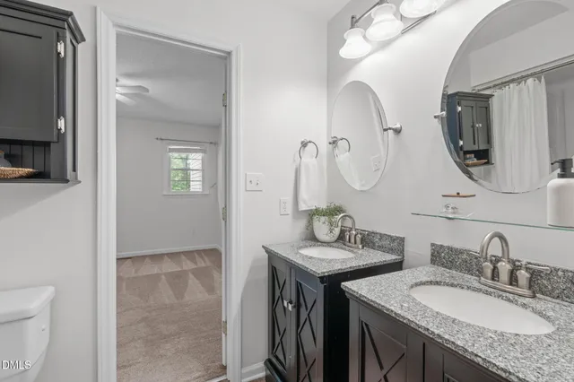 a bathroom with a granite countertop sink a toilet and a mirror