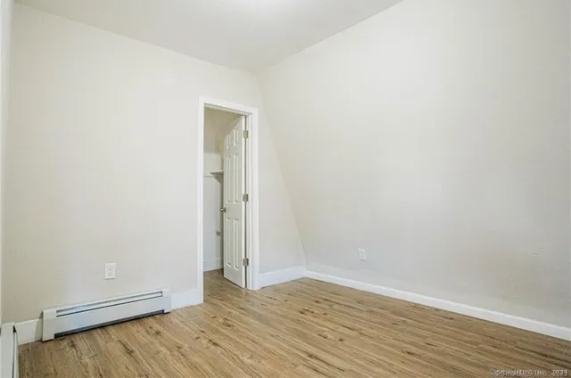 a view of an empty room with wooden floor and closet