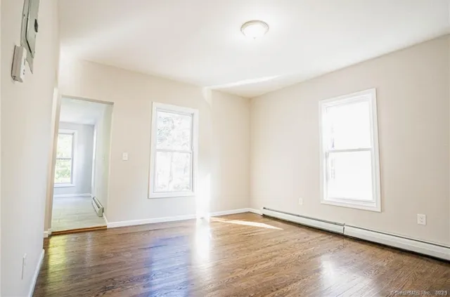 an empty room with wooden floor and windows