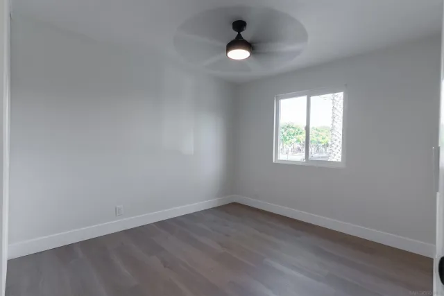 a view of an empty room with a window and kitchen view