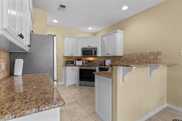 a kitchen with granite countertop white cabinets and stainless steel appliances