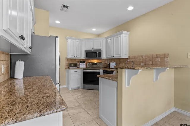 a kitchen with granite countertop white cabinets and stainless steel appliances