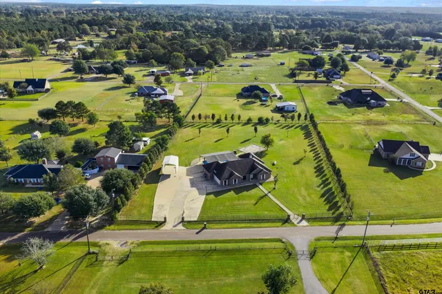 an aerial view of a house with swimming pool and large trees