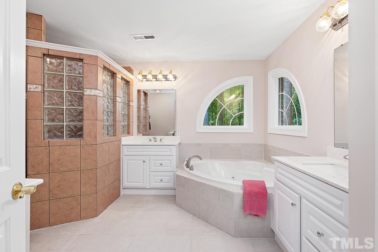 2113 Tibwin Drive Raleigh, NC 27606 - Photo 15 of 30 Recently updated, the primary bath boasts dual vanities, jetted tub, and walk-in doorless shower.