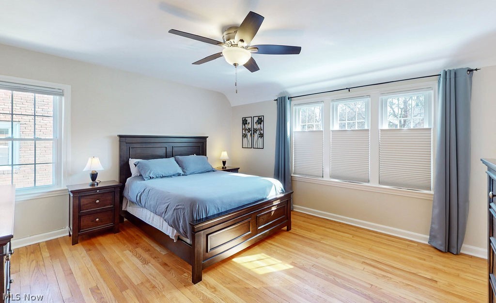 2556 Channing Road Cleveland, OH 44118 - Photo 14 of 34 A view of the primary bedroom with light hardwood floors, ceiling fan, and several windows with views of the front and side of the house