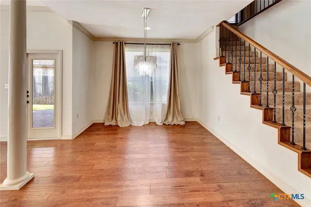 a view of an empty room with wooden floor and stairs