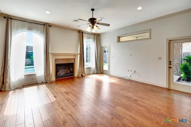 an empty room with wooden floor fireplace and windows