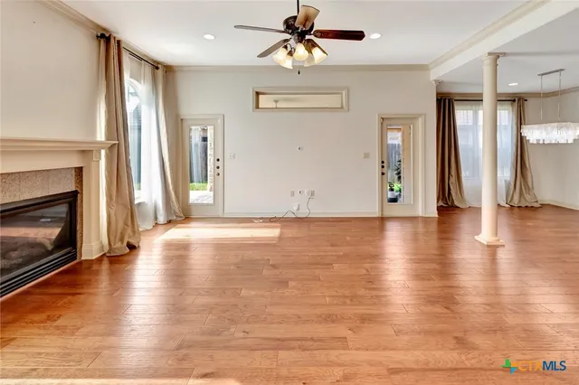 an empty room with wooden floor fireplace and windows