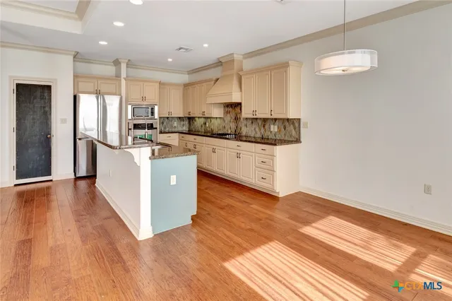 a kitchen with stainless steel appliances granite countertop a refrigerator a sink dishwasher a stove and white countertops with wooden floor