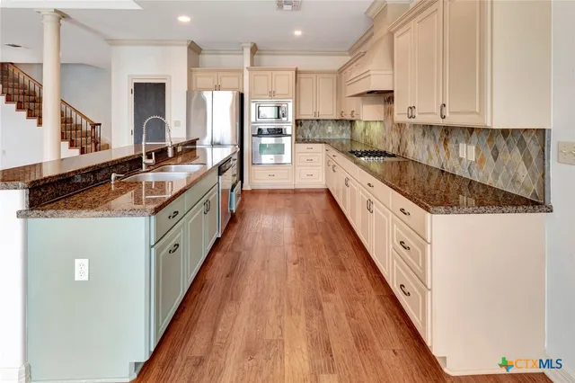 a large kitchen with stainless steel appliances granite countertop a large counter top a stove a sink and a refrigerator