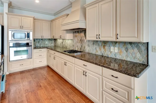 a kitchen with granite countertop white cabinets and stainless steel appliances