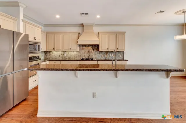 a kitchen with stainless steel appliances granite countertop a refrigerator a sink and a stove