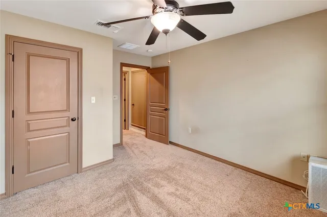 an empty room with closet and a chandelier fan