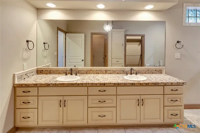 a bathroom with a granite countertop double vanity sink and mirror