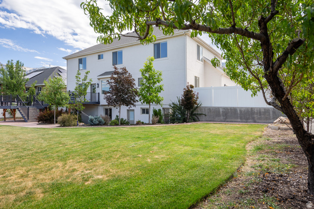 868 Braddock Lane Alpine, UT 84004 - Photo 62 of 64 Spacious backyard featuring a large green lawn, mature trees, and a white privacy fence